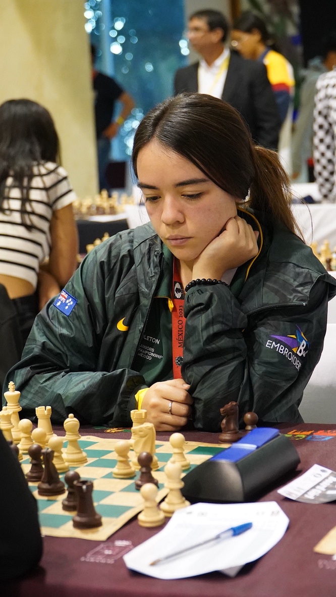 Jody Middleton deep in thought at the board, wearing the Australian team jacket